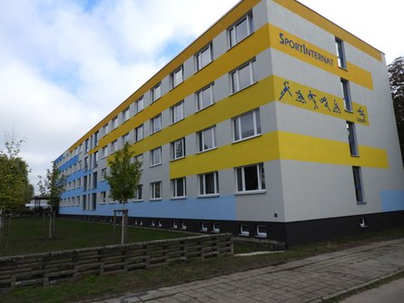 Blau-Orange-Gelb gestrichen und mit Sportpiktogrammen versehen ist unverkennbar, dass es sich bei diesem Gebäude um das Sportinternat handelt.