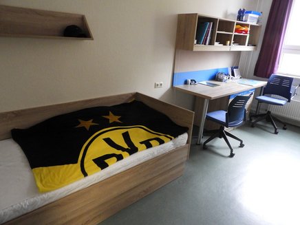 Zimmer Auf jeder Seite befindet sich ein Bett, ein Schreibtisch, ein Nachtschrank und ein großer Kleiderschrank. Gemütlich eingerichtet kann sich jede*r wohl fühlen.