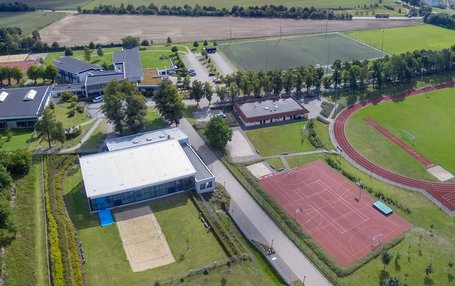 Sportstätten der Landessportschule Luftaufnahme der Außensportanlagen der Landessportschule. Man sieht die Rasenplätze, die Schwimmhalle mit Beachvolleyballplatz, Tartanplätze und die Sporthalle